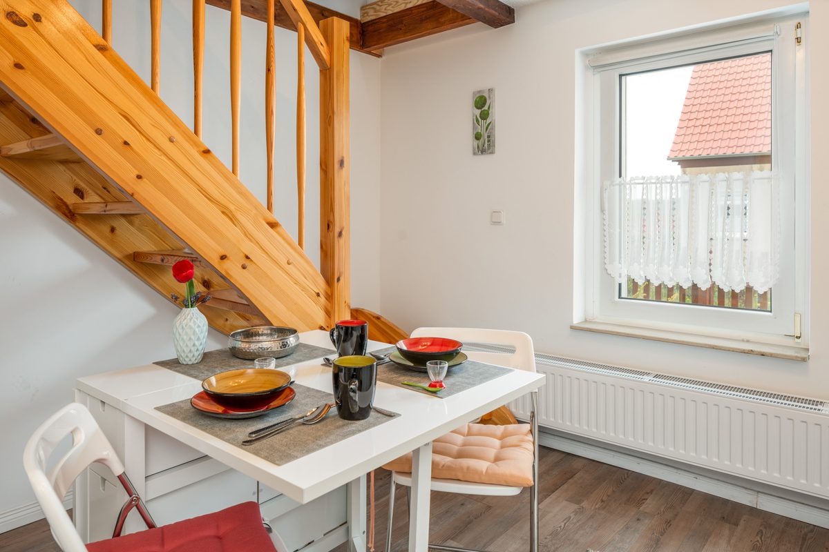 Gedeckter Essplatz am Fenster unter der Holztreppe