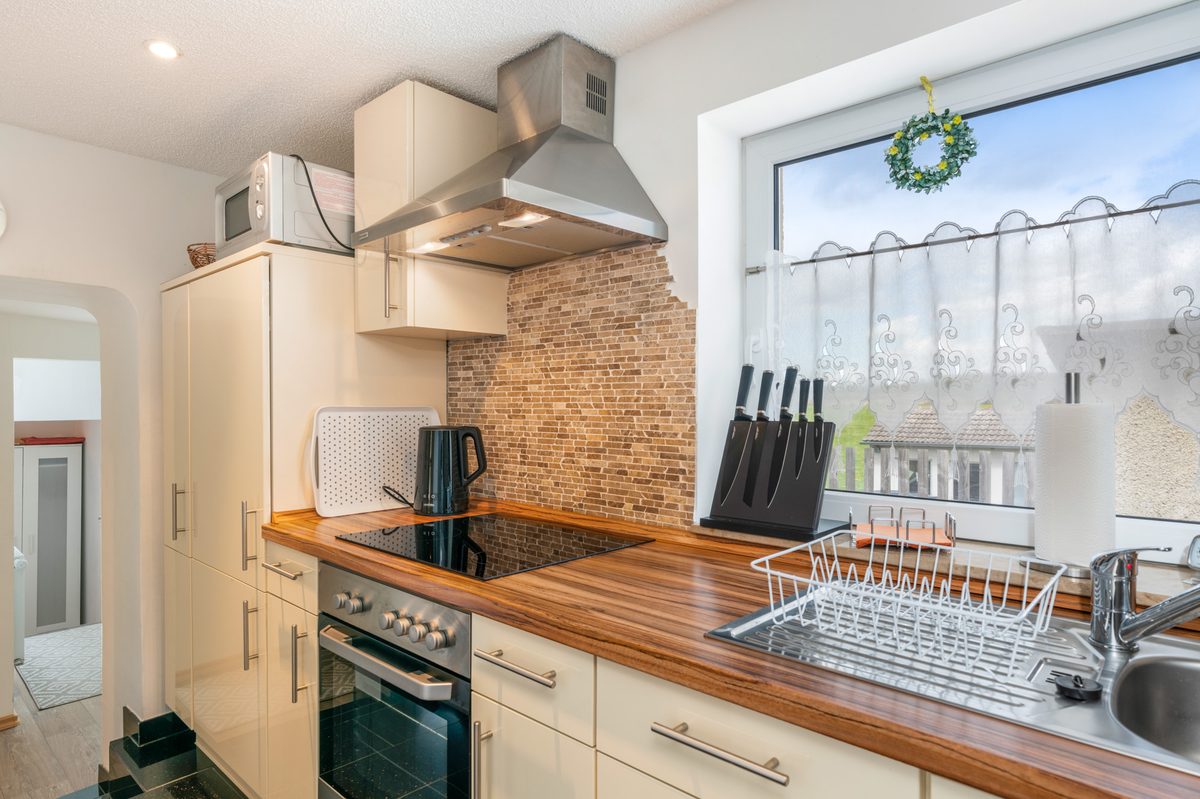 Separate Küche mit Backofen, Dunstabzug und großem Fenster