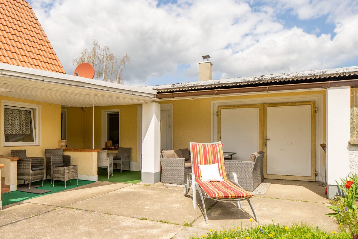 Überdachte Terrasse mit Sonnenliegen und Gartenmöbeln